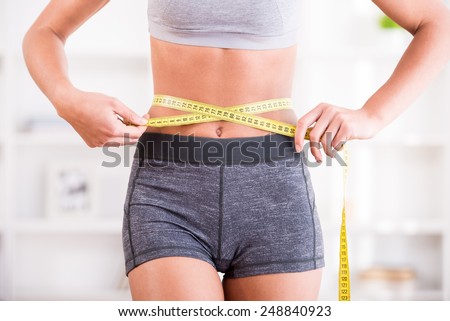 Sporty woman and measure around her body at home.