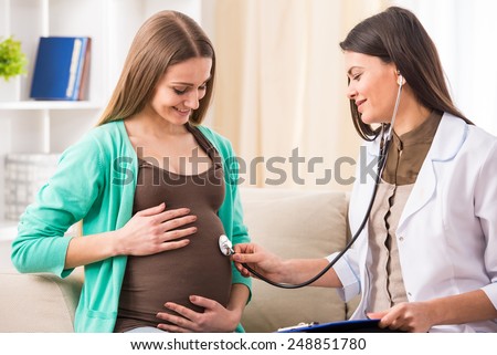 Consultation of pregnant young woman with doctor in hospital.
