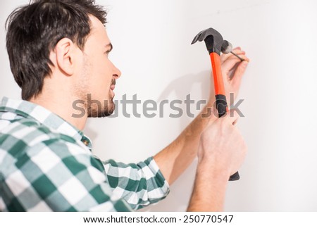 Repair home concept. Young man hammer a nail.