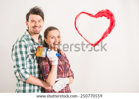 Portrait of young happy couple painted a heart on the wall while doing repair at home.