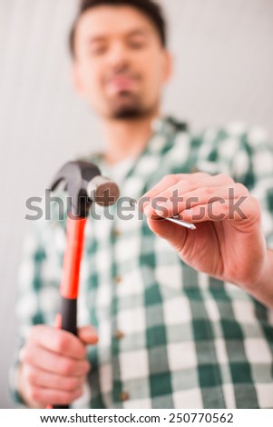 Repair home concept. View from below young man hammer a nail.