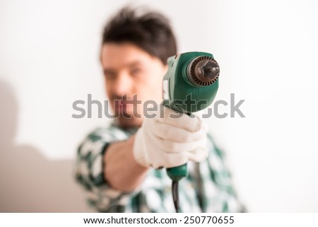 Close-up of young man is holding electric drill. Focus on drill.