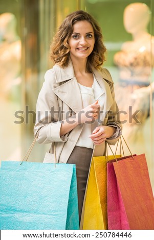 Beauty woman with shopping bags in shopping mall is looking at the camera. Sales. Shopping Center.