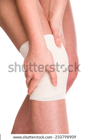 Female is wrapping her knee injury with bandage.