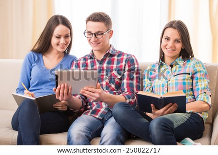 Education and people concept. Group of students are sitting on the sofa, with tablet and book.