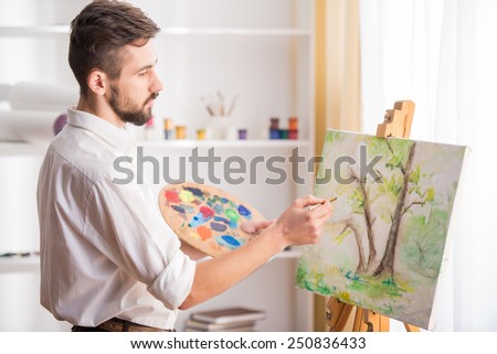 Side view of highly gifted painter while he is painting his picture.