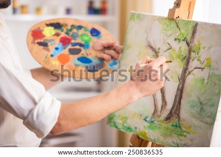 Close-up view of highly gifted painter while he is painting his picture.