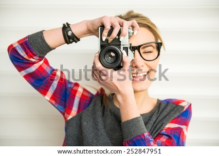 Close-up of trendy girl face in sunglasses with vintage camera.