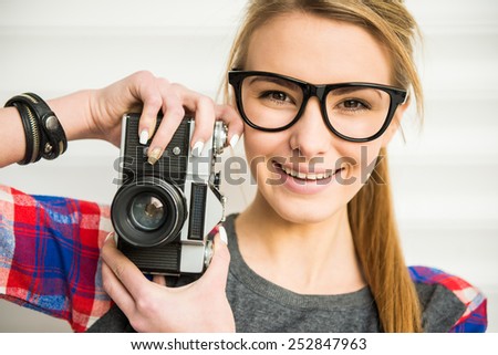 Close-up of trendy girl face in sunglasses with vintage camera.