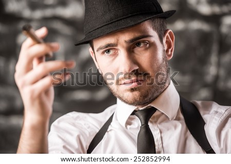 Close-up of a gangster man is smoking a cuban cigar.