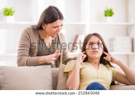 Problems between generations concept. Teen closed his ears with his hands while her mom yells at her.