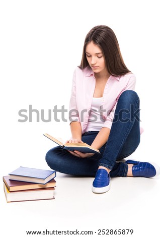 Beautiful girl is sitting on the floor and reading a book, isolated on white background.