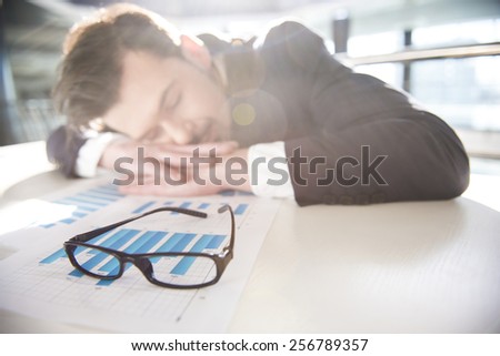 Young businessman is sleeping at the table at work.