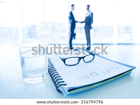 Focus on the things on the table. Blurred men near panoramic windows on background.