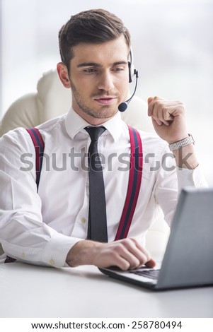 Businessman is taking a call on a headset as he deals with queries at the customer support call centre.