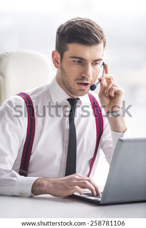 Businessman is taking a call on a headset as he deals with queries at the customer support call centre.