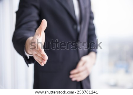 Businessman is wearing in suit, handshake to you.