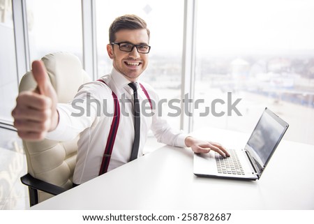 Young smiling businessman is showing thumb up while working in office.