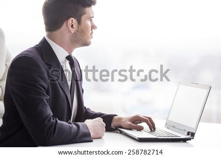 Side view of young businessman is working with laptop in office.