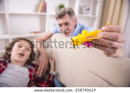 Toddler boy and his grandpa are playing with plane toy.