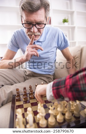 Senior caucasian man is playing chess with a boy.