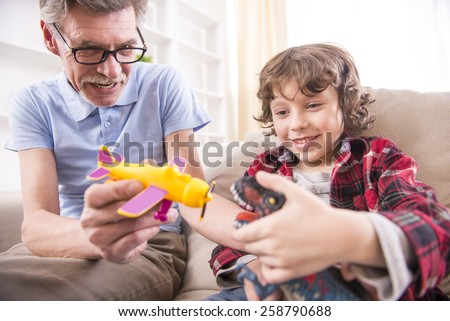 Toddler boy and his grandpa are playing with a plane toy.