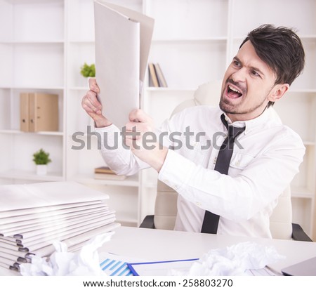 Angry businessman working in office and holding a paper
