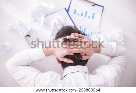 Businessman holds hands on his head and looks at documents.View from above
