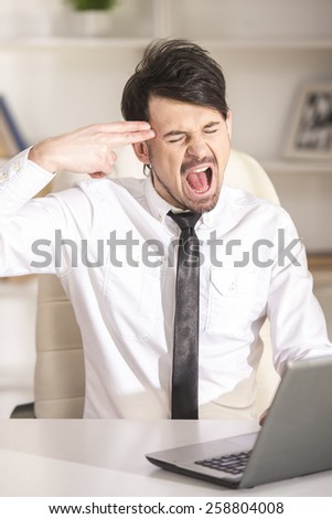 Tired businessman is working with laptop and holding fingers to his temple