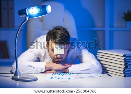 Frustrated young businessman in his office with note on his forehead. He needs help.