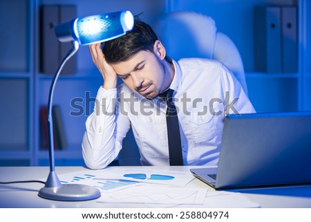 Tired businessman in his office is working with documents.
