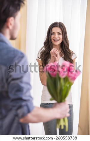 Man is giving a bunch of flowers and happy woman at home.