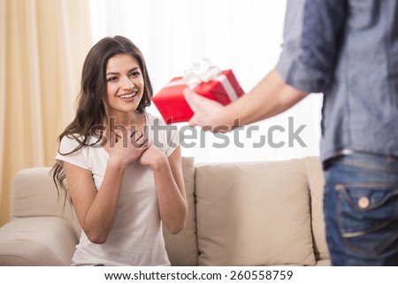 Man is giving a present to his girlfriend at home.