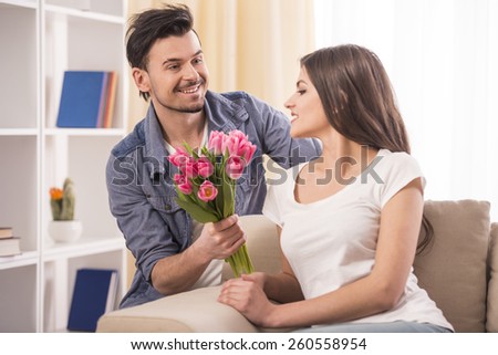 Boyfriend is giving flowers to his beautiful girlfriend at home.