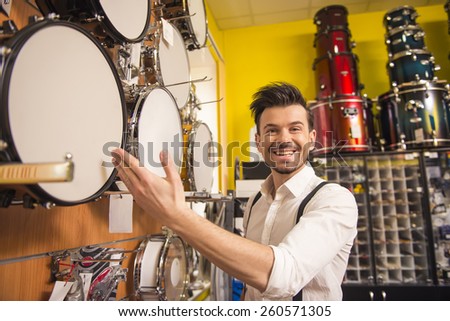 Young man is looking at drums in the music store.