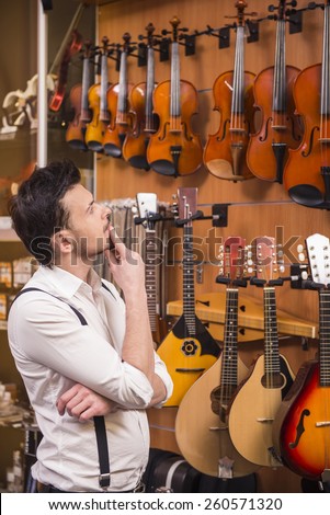 Young man is choosing violin in a music store.