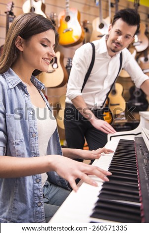 Young girl is playing piano in a music store.