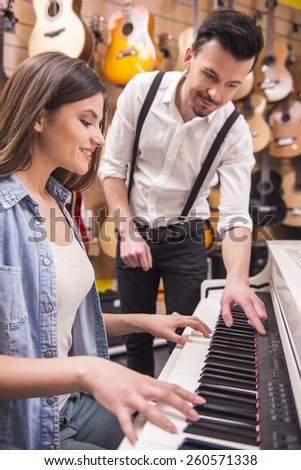 Young girl is playing the piano with man in the music store.