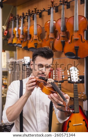 Young man is considering violin in a music store.