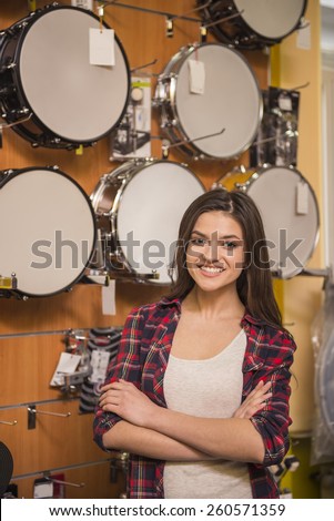 Young attractive girl on the background of drums in the music store.