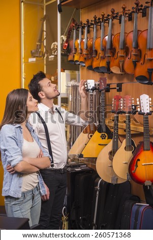 Young girl and man are choosing violin in a music store.
