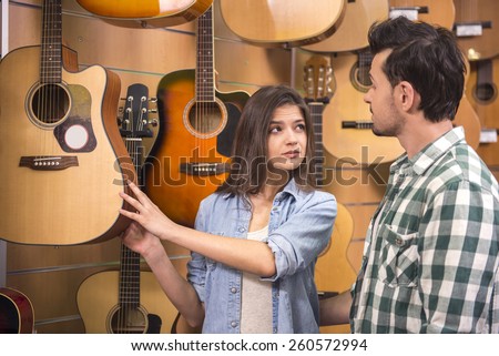 Young girl is showing husband guitar in music store.