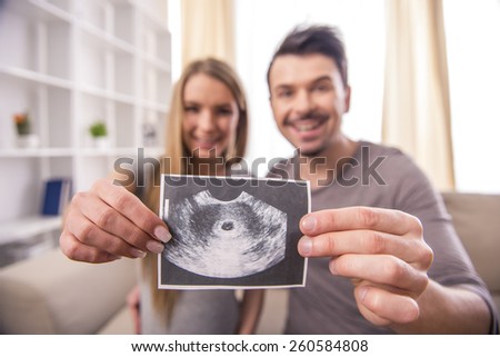 Happy couple are holding ultrasound scan of their baby.
