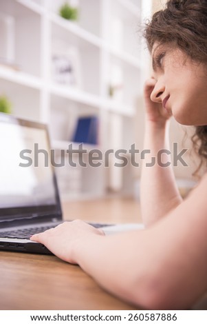 Young beautiful woman is using a laptop computer at home. Focus on laptop.
