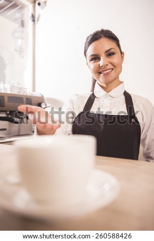 Pretty young barista is offering cup of coffee in a cafe.