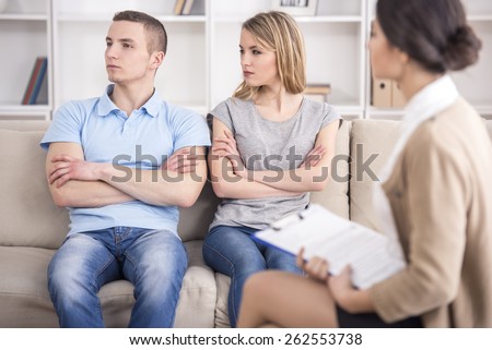 Young couple sitting on the sofa after quarrel. Psychologist