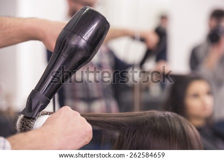 Close-up hairdresser blow dry for client hair in hairdressing salon.