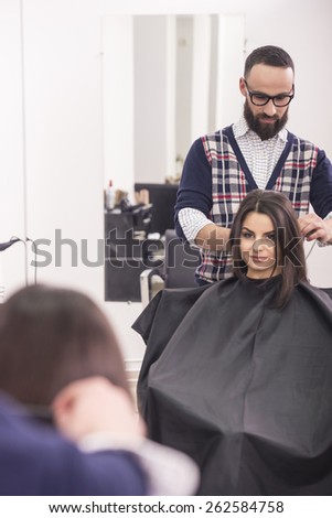 Professional hairdresser making hair for a brunette girl in hairdresser salon.
