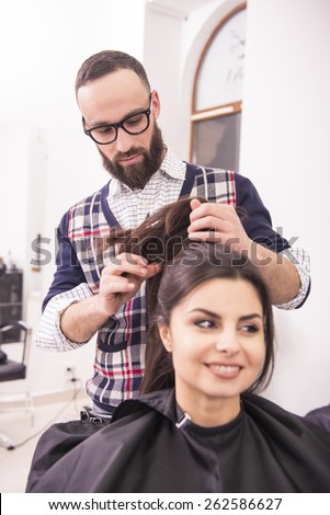 Professional hairdresser making hair for a brunette girl in hairdresser salon.