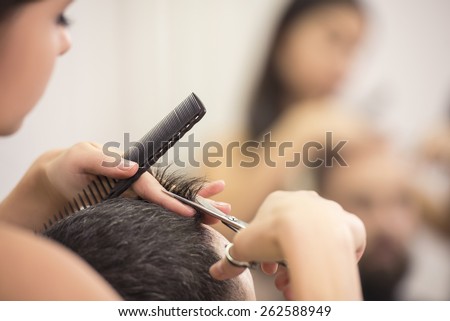 Close-up hairdresser with scissors and comb. Blurred background.